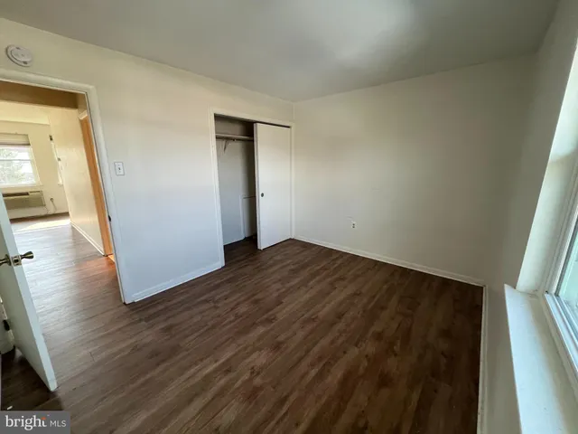 a view of an empty room with wooden floor and closet