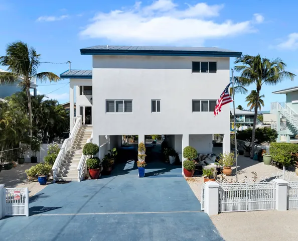 a view of a white house with a small yard and a car parked in front of it