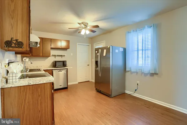 a kitchen with stainless steel appliances granite countertop a refrigerator a sink dishwasher a stove and a dining table with wooden floor
