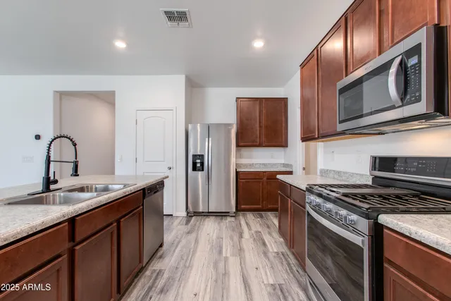 a kitchen with stainless steel appliances granite countertop a stove a sink and a refrigerator