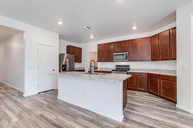 a kitchen with stainless steel appliances granite countertop a stove top oven a sink dishwasher a refrigerator and a oven with wooden cabinets