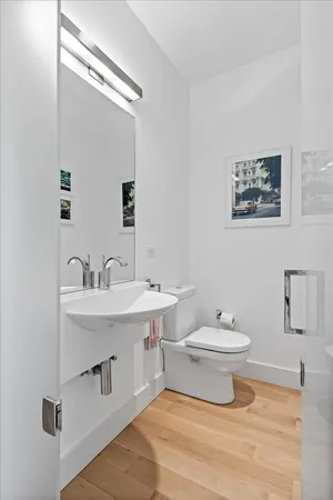 a kitchen with stainless steel appliances a white refrigerator a stove a sink dishwasher and white cabinets with wooden floor