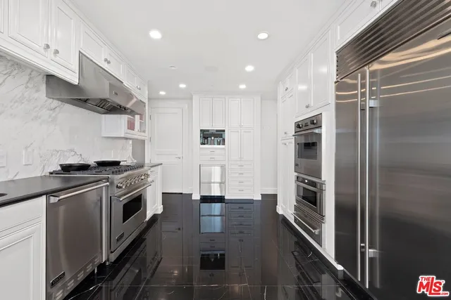 a kitchen with stainless steel appliances a refrigerator a stove and white cabinets