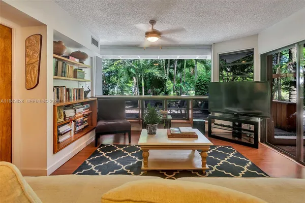 a living room with furniture a flat screen tv and a floor to ceiling window