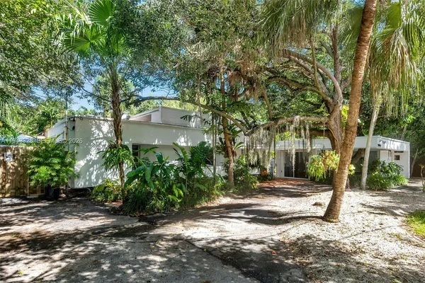 a pathway of a house with a yard and large trees