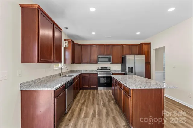 a large kitchen with stainless steel appliances granite countertop plenty wooden cabinets counter space a sink and a stove