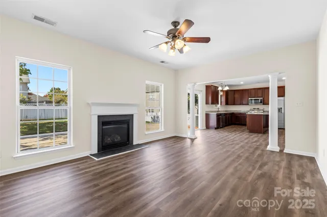 a view of a livingroom with a fireplace a ceiling fan and wooden floor