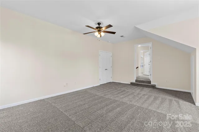 an empty room with closet and a ceiling fan
