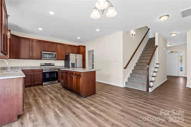 a kitchen with stainless steel appliances kitchen island granite countertop wooden cabinets a stove top oven a sink and dishwasher