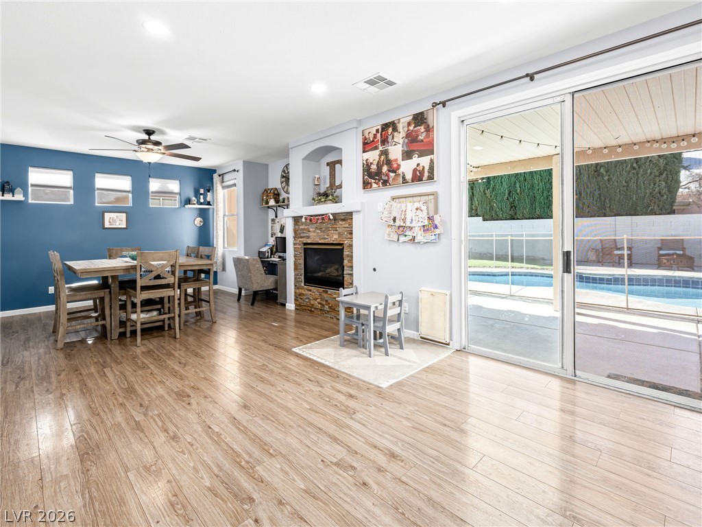 2199 Maple Shade Street Henderson, NV 89002 - Photo 11 of 75 Dining space with baseboards, wood Living area with baseboards, a stone fireplace, and luxury vinyl plank flooring