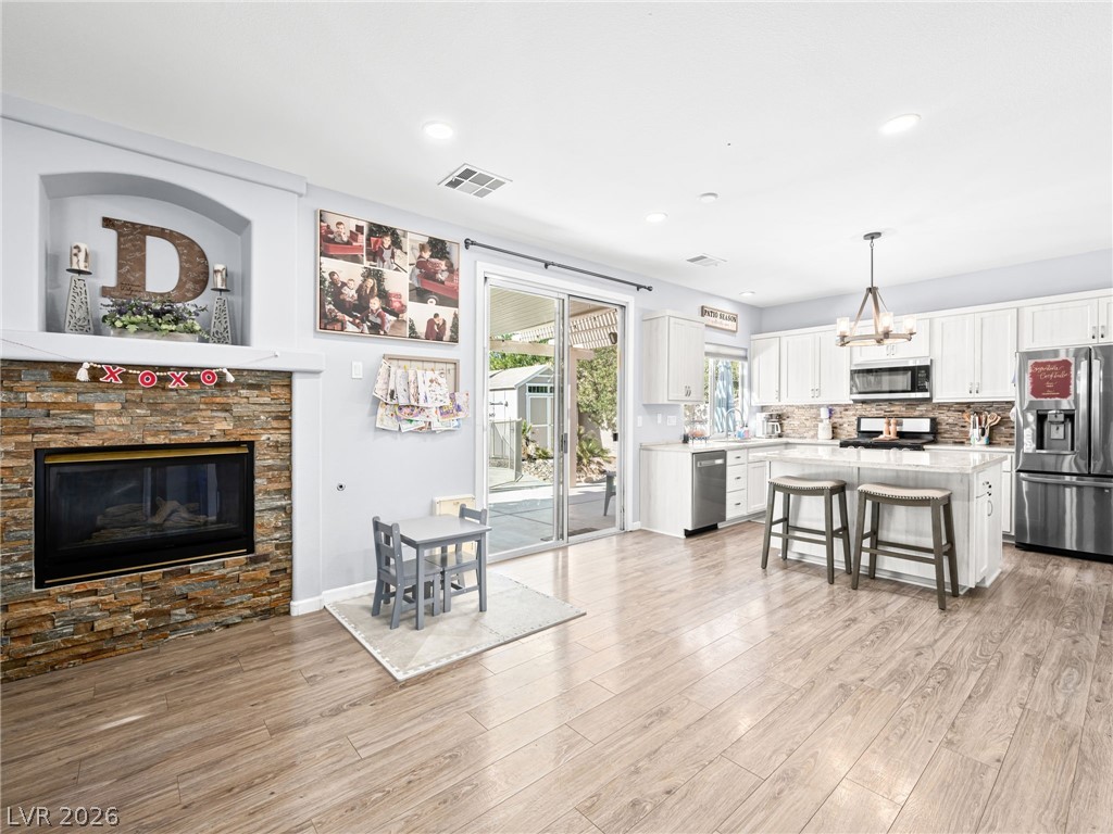 2199 Maple Shade Street Henderson, NV 89002 - Photo 12 of 75 Dining space with baseboards, wood Living area with baseboards, a stone fireplace, and luxury vinyl plank flooring