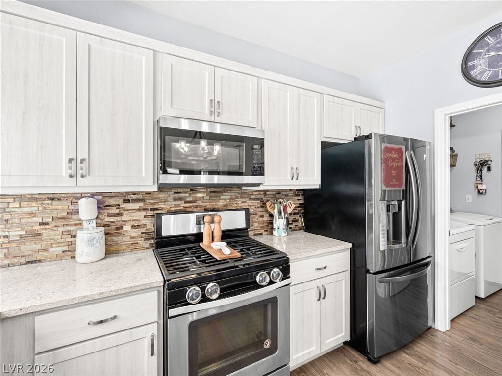 2199 Maple Shade Street Henderson, NV 89002 - Photo 19 of 75 Updated kitchen showcasing refaced cabinets, a stylish backsplash, center island, stainless steel appliances, and durable luxury vinyl plank flooring.