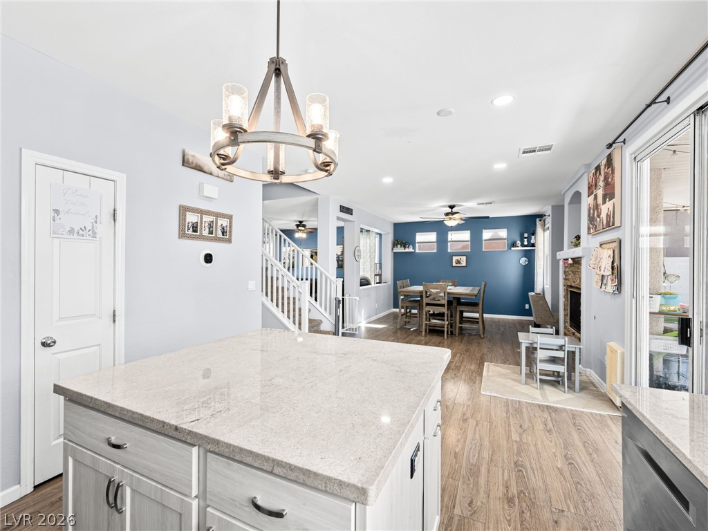 2199 Maple Shade Street Henderson, NV 89002 - Photo 20 of 75 Updated kitchen showcasing refaced cabinets, a stylish backsplash, center island, stainless steel appliances, and durable luxury vinyl plank flooring.