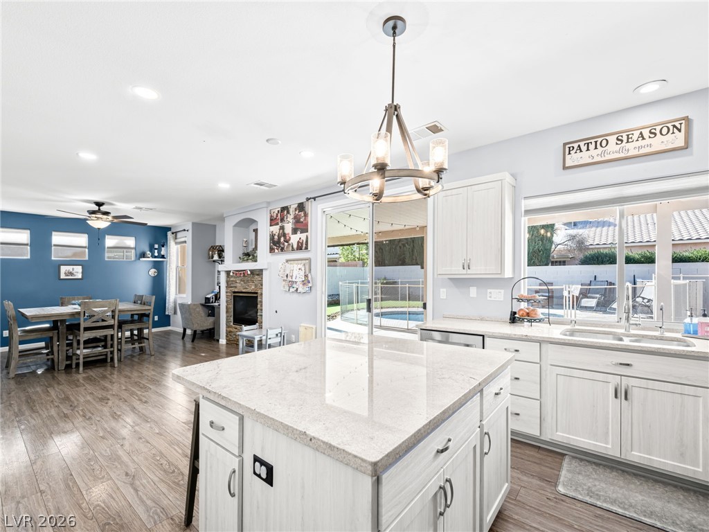2199 Maple Shade Street Henderson, NV 89002 - Photo 21 of 75 Updated kitchen showcasing refaced cabinets, a stylish backsplash, center island, stainless steel appliances, and durable luxury vinyl plank flooring.