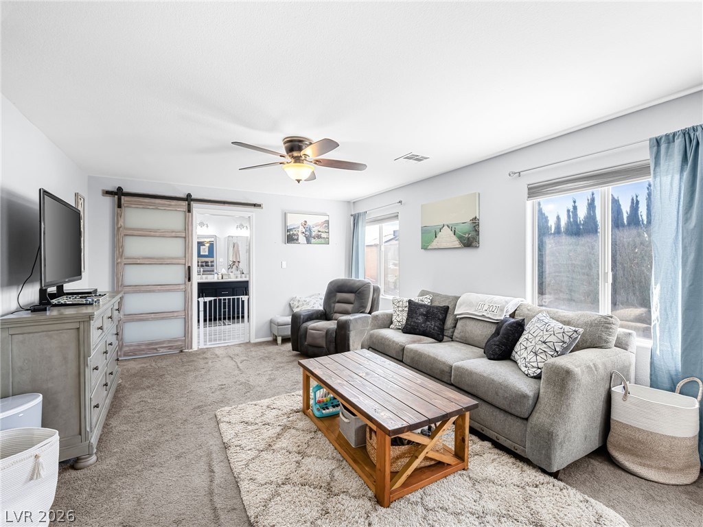 2199 Maple Shade Street Henderson, NV 89002 - Photo 35 of 75 Primary bedroom suite featuring carpeted flooring, baseboards, and a custom barn door leading to the ensuite. This massive, private suite includes a dedicated living area, bedroom, and ensuite bathroom, creating a separate wing for added privacy and comfort.