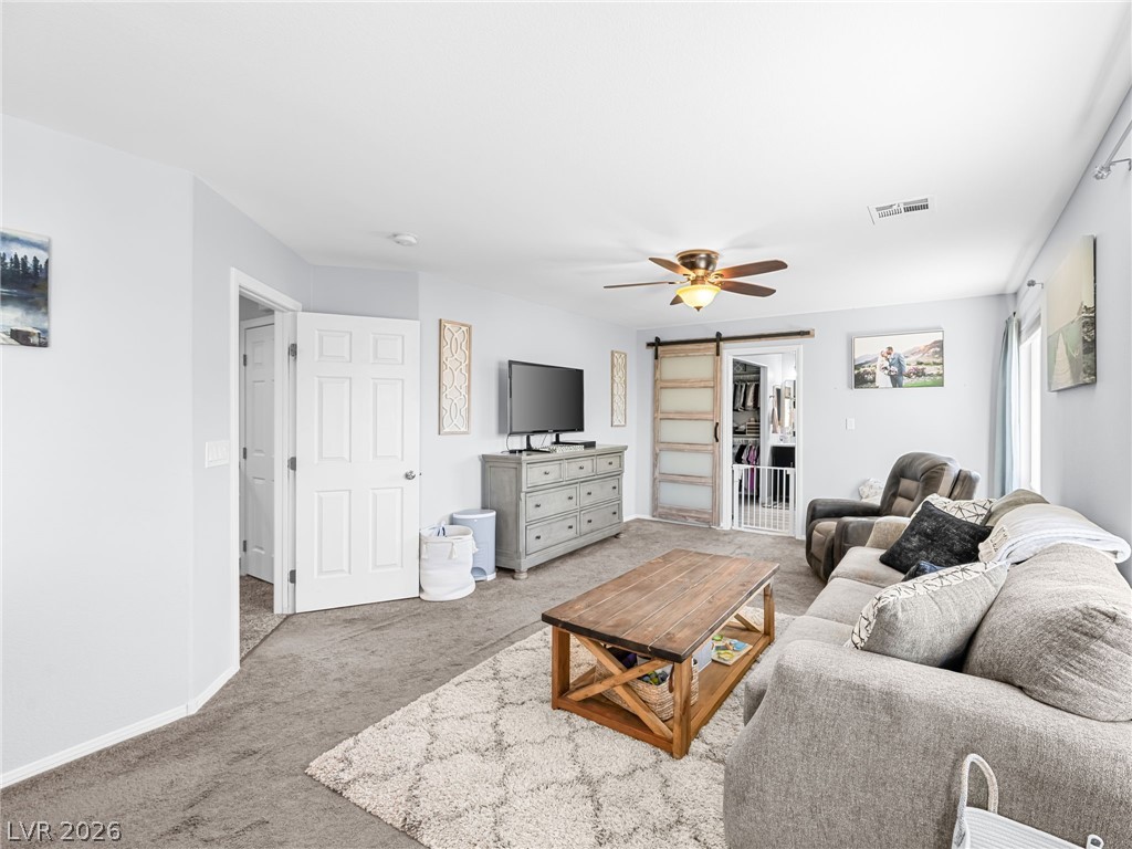 2199 Maple Shade Street Henderson, NV 89002 - Photo 36 of 75 Primary bedroom suite featuring carpeted flooring, baseboards, and a custom barn door leading to the ensuite. This massive, private suite includes a dedicated living area, bedroom, and ensuite bathroom, creating a separate wing for added privacy and comfort.