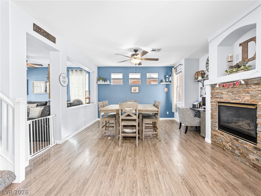 2199 Maple Shade Street Henderson, NV 89002 - Photo 8 of 75 Dining space with baseboards, wood Living area with baseboards, a stone fireplace, and luxury vinyl plank flooring
