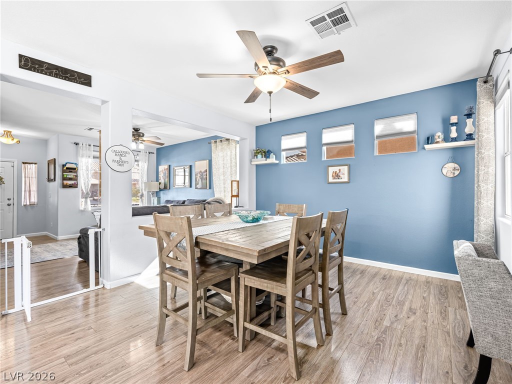 2199 Maple Shade Street Henderson, NV 89002 - Photo 10 of 75 Dining space with baseboards, wood Living area with baseboards, a stone fireplace, and luxury vinyl plank flooring