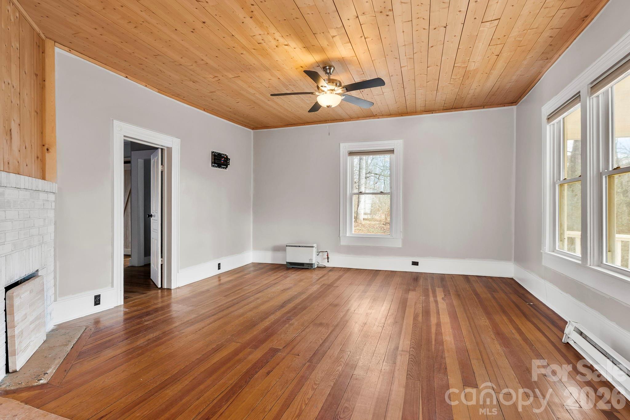 42 Old Patton Hill Road Swannanoa, NC 28778 - Photo 4 of 33 an empty room with wooden floor chandelier fan and windows