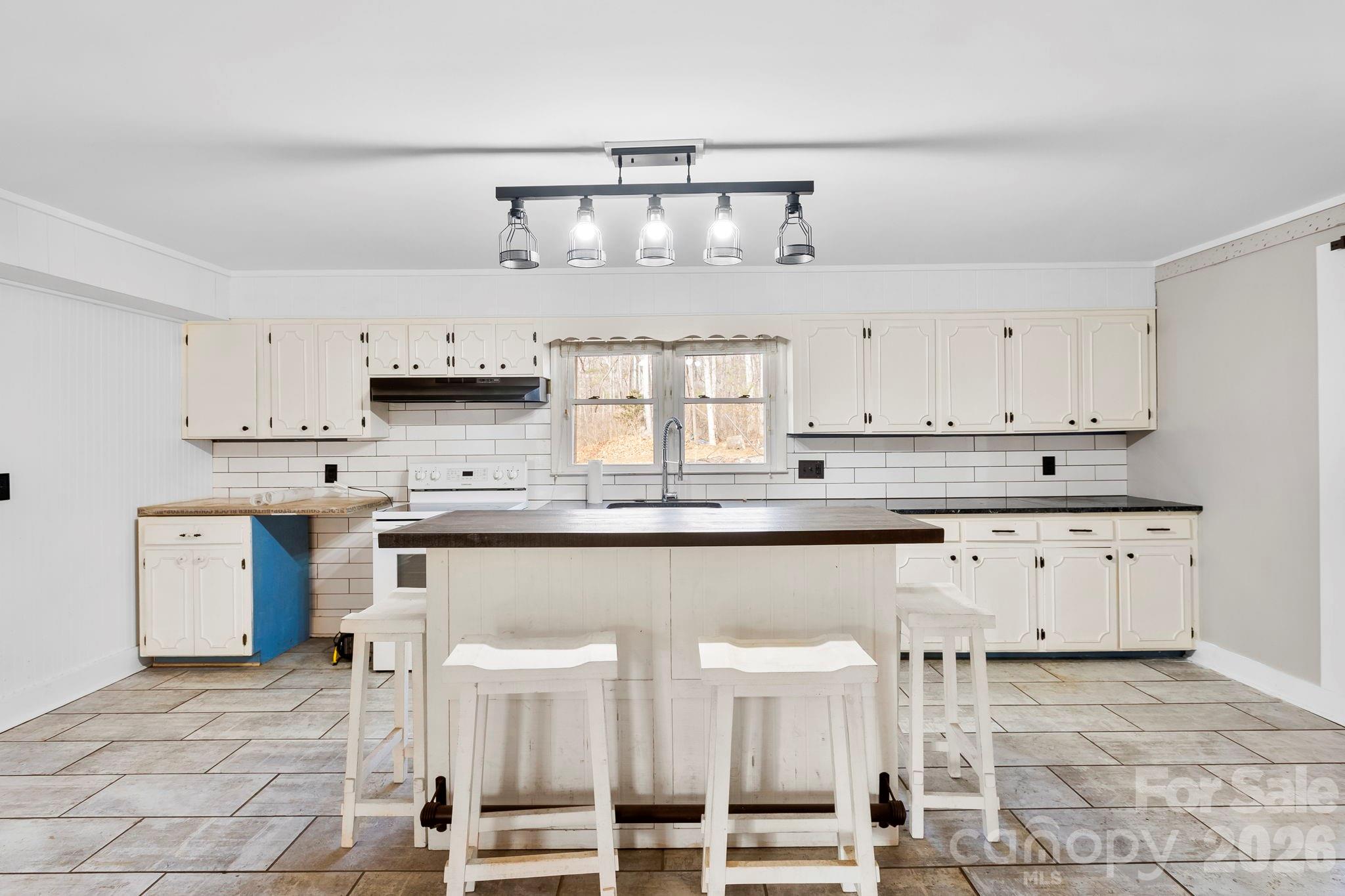42 Old Patton Hill Road Swannanoa, NC 28778 - Photo 10 of 33 a kitchen with granite countertop white cabinets and chairs