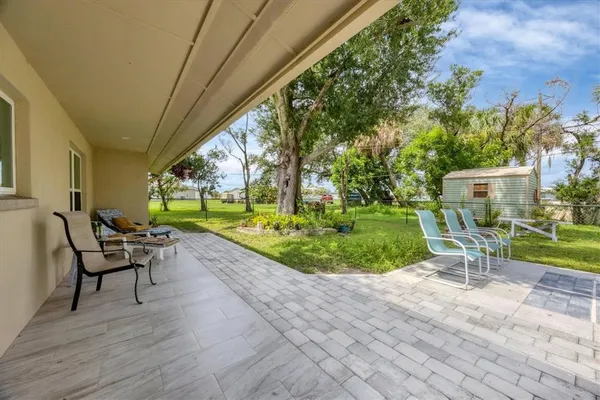 a view of a backyard with table and chairs potted plants and large tree