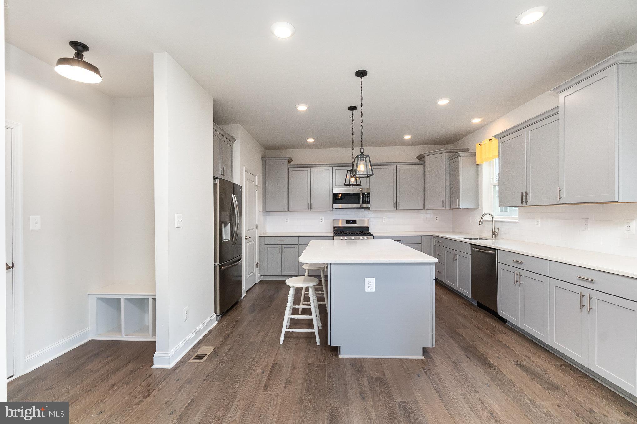 1126 Up And Over Lane Aberdeen, MD 21001 - Photo 11 of 46 a kitchen with a stove a sink dishwasher a refrigerator and white cabinets with wooden floor