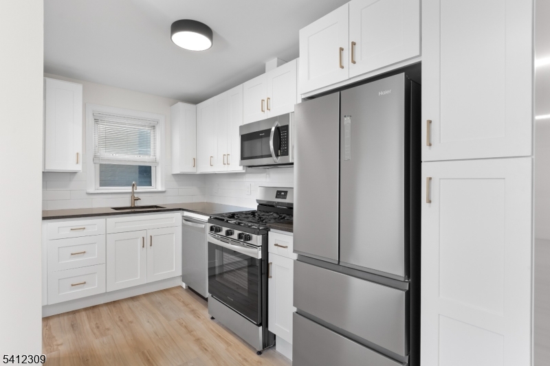 676 Chestnut Street, Unit 1 Kearny, NJ 07032 - Photo 11 of 27 a kitchen with cabinets stainless steel appliances and wooden floor