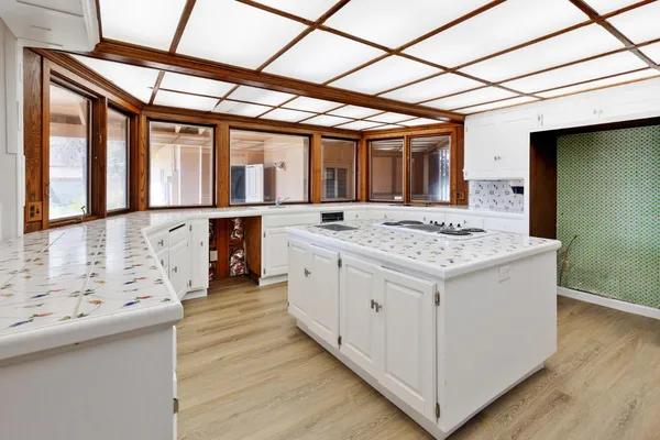 a large white kitchen with a sink and a large window