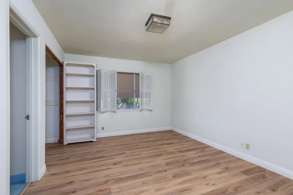 a view of a bedroom with wooden floor and a window
