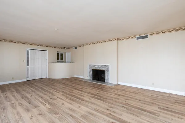a view of empty room with wooden floor fireplace and windows