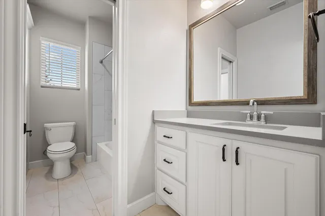 a bathroom with a granite countertop sink toilet and mirror