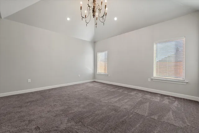 en empty room with windows and chandelier fan