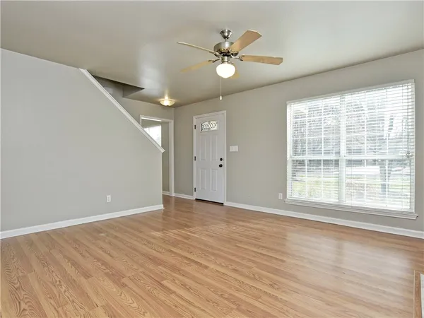 a view of an empty room with wooden floor and a window