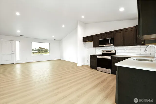 a kitchen with stainless steel appliances a stove top oven a sink dishwasher and microwave with wooden floor