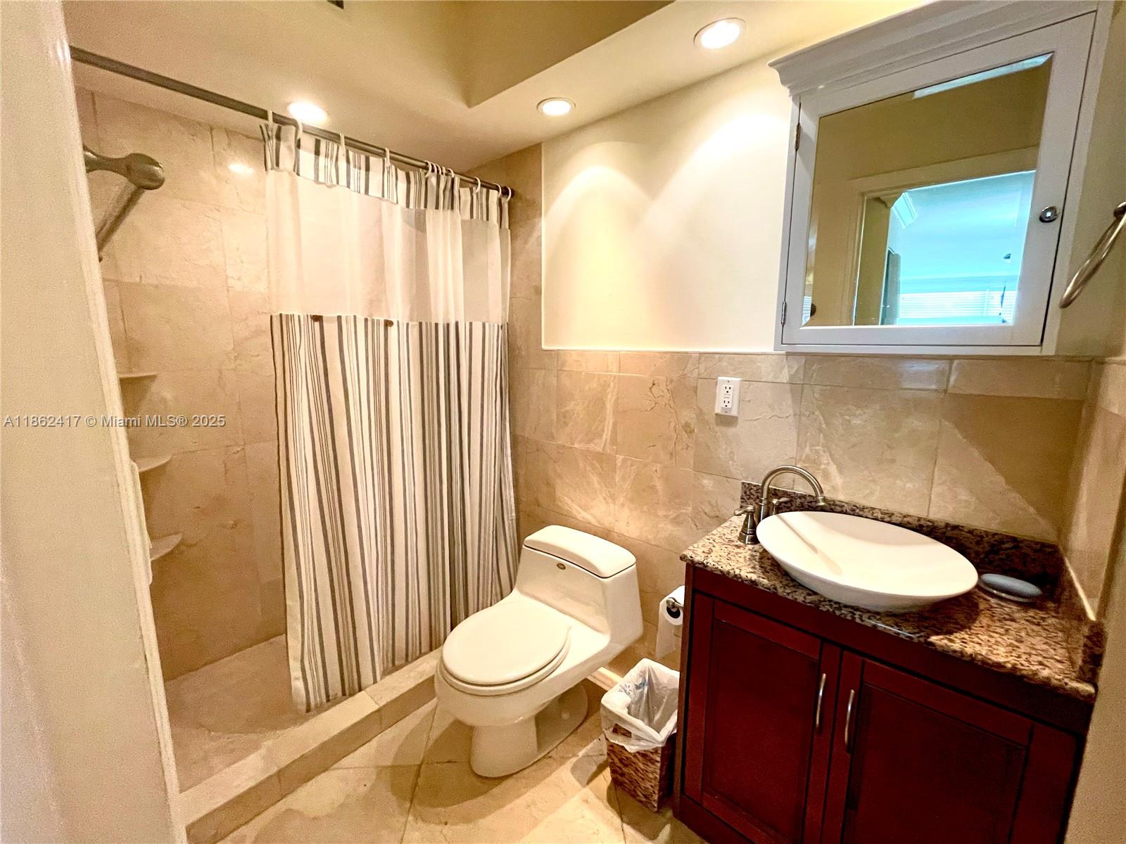 177 Ocean Ln Drive, Unit 209 Key Biscayne, FL 33149 - Photo 16 of 19 a bathroom with a granite countertop sink toilet a mirror and shower