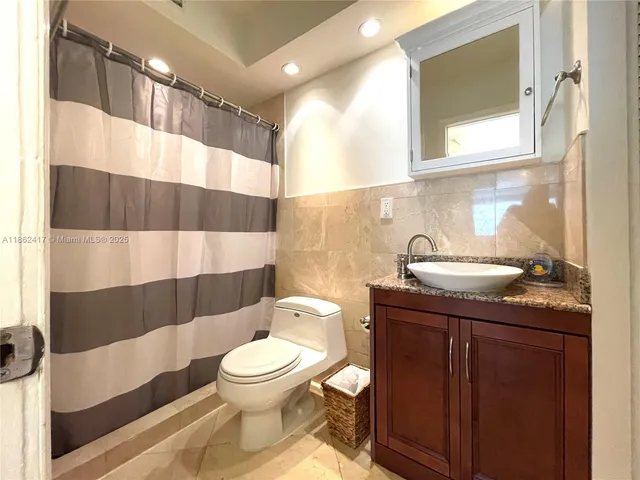 a bathroom with a granite countertop toilet sink and mirror