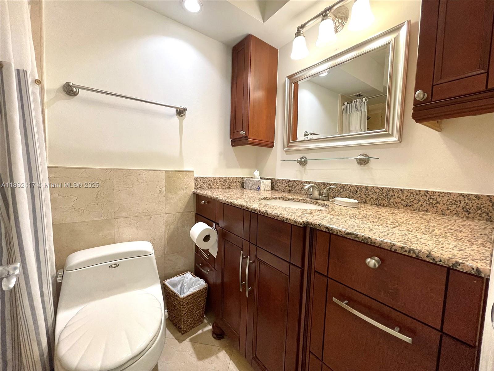 177 Ocean Ln Drive, Unit 209 Key Biscayne, FL 33149 - Photo 18 of 19 a bathroom with a granite countertop toilet sink and mirror