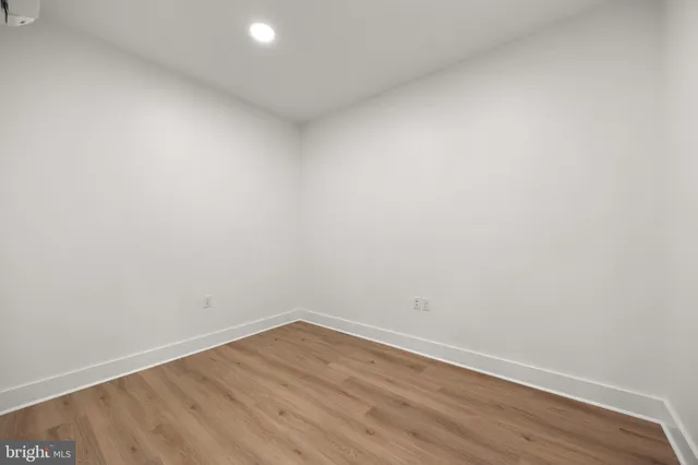 a view of an empty room with wooden floor and white walls