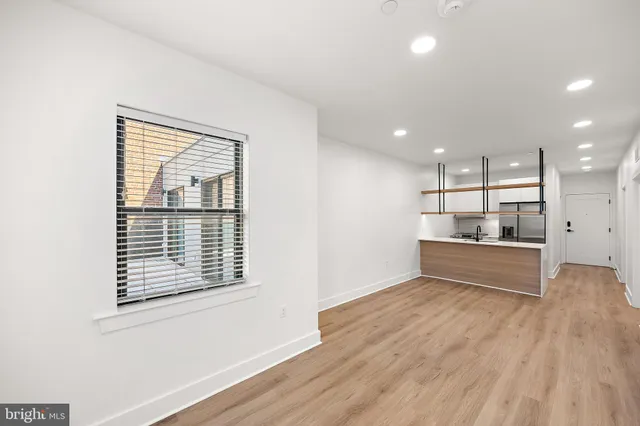a view of kitchen with stainless steel appliances wooden floor and window