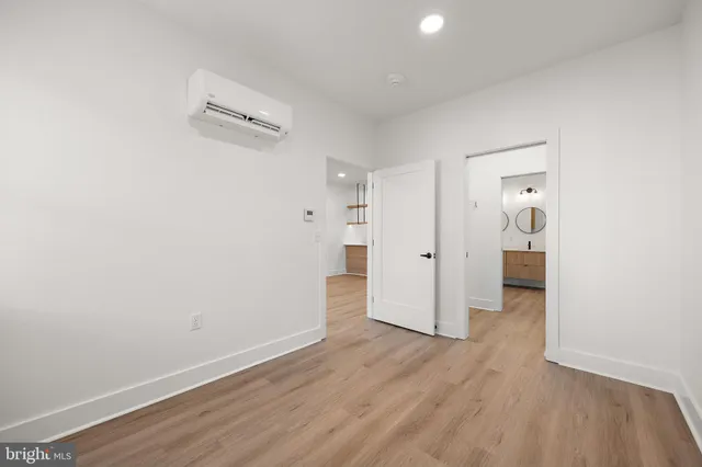 a view of a hallway with wooden floor and a bathroom