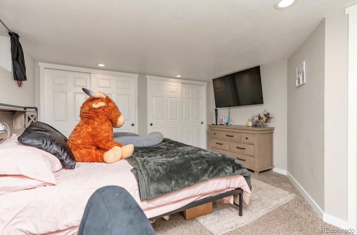 9271 Travis Street Thornton, CO 80229 - Photo 11 of 25 a bedroom with a bed and a flat tv screen on wall