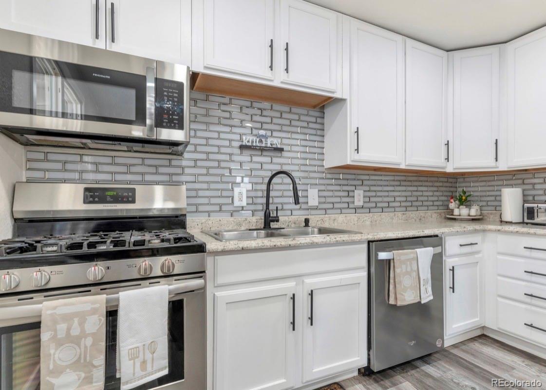 9271 Travis Street Thornton, CO 80229 - Photo 4 of 25 a kitchen with white cabinets stainless steel appliances and sink