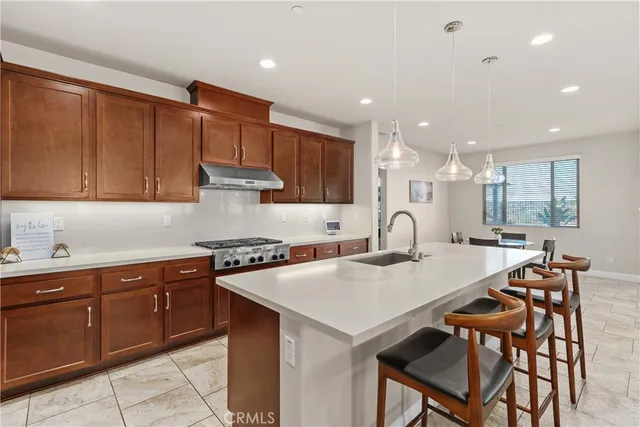 a kitchen with stainless steel appliances granite countertop a table chairs sink and cabinets