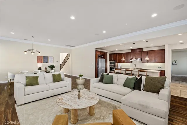 a living room with furniture kitchen view and a wooden floor