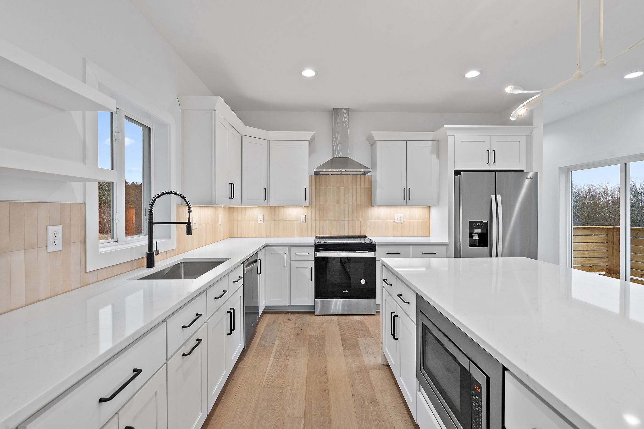 a large kitchen with stainless steel appliances granite countertop a white cabinets a sink and a refrigerator
