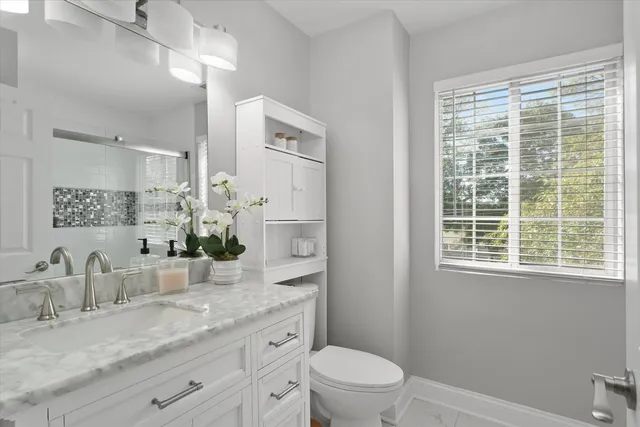 a bathroom with a granite countertop sink mirror vanity and toilet