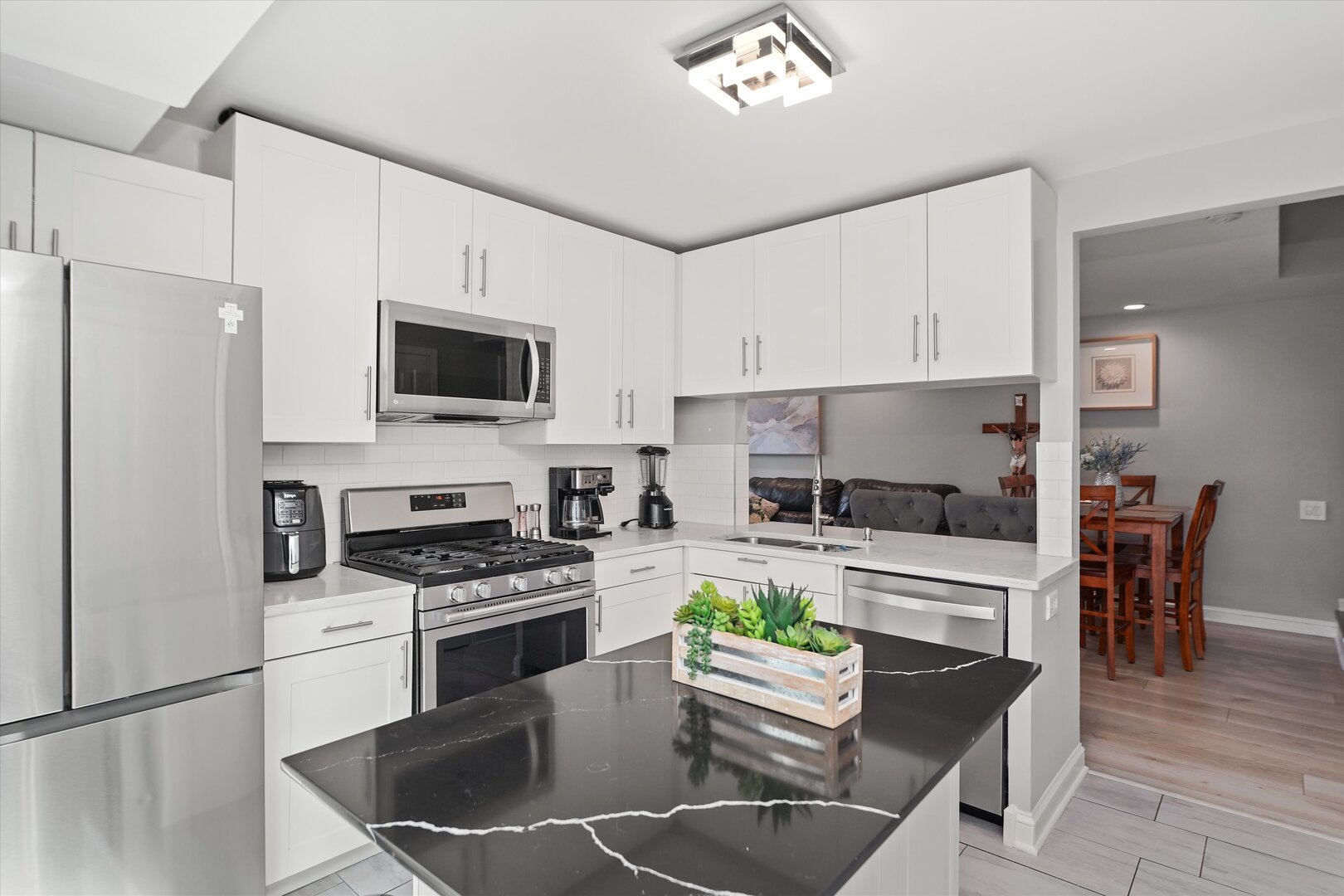 1334 Normantown Road Naperville, IL 60564 - Photo 6 of 19 a kitchen with stainless steel appliances kitchen island granite countertop a stove a sink a microwave a refrigerator a dining table and chairs with wooden floor