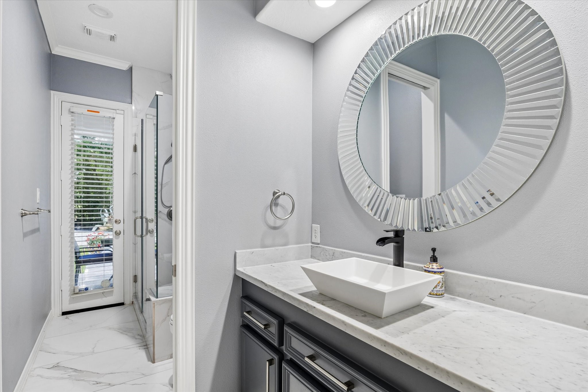 35 North Regent Oak Spring, TX 77381 - Photo 24 of 43 This beautifully updated secondary bath combines style and functionality with elegant finishes, a quartz vanity, designer vessel sink, and walk-in shower. Conveniently located with direct access to the patio and pool area, it allows guests to transition effortlessly from outdoor activities without tracking through the main living spaces. Thoughtfully designed for both everyday convenience and entertaining, this bath is a valuable feature for indoor-outdoor living.