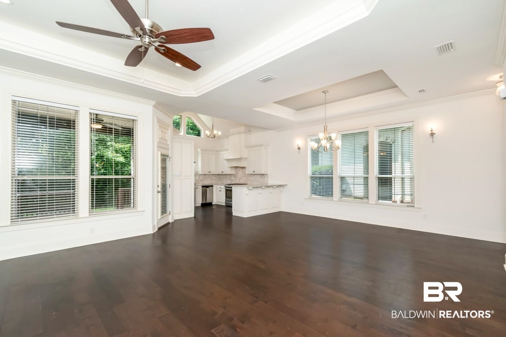3528 Rue Royal Mobile, AL 36693 - Photo 19 of 53 Expansive open-concept room featuring dark wood-finish flooring, white walls, and a multi-tiered tray ceiling with crown molding