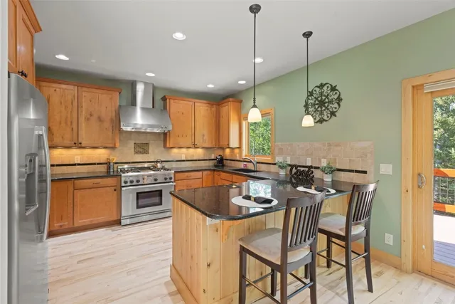 a kitchen with stainless steel appliances granite countertop a sink a stove a refrigerator and island with wooden floor
